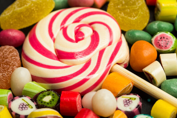 close up view of bright lollipop among fruit caramel multicolored candies