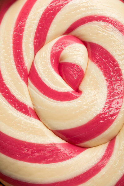 close up view of swirl pink and beige delicious shiny sweet lollipop
