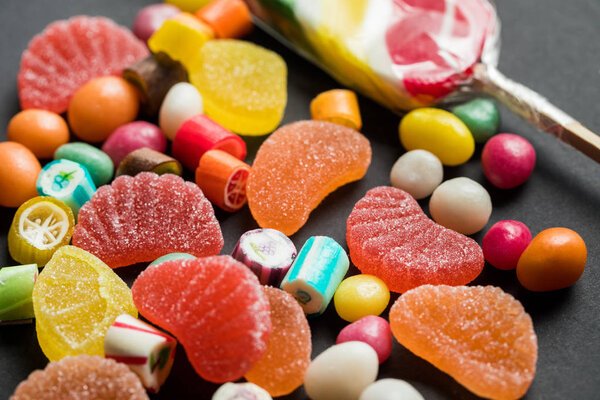 selective focus of delicious caramel and jelly sweets on black background