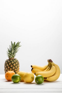 Sarı muzlar tatlı ananasın yanında, limonlar, portakal ve limonlar beyaz üzerine 