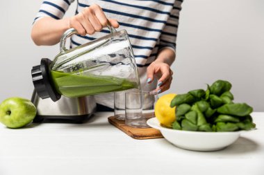 gri elma yakın cam lezzetli yeşil smoothie döken kadın kırpılmış görünümü 