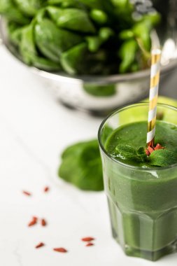 beyaz üzerinde ıspanak yaprakları yakınında saman ile cam goji çilek ve nane ile lezzetli smoothie seçici odak 