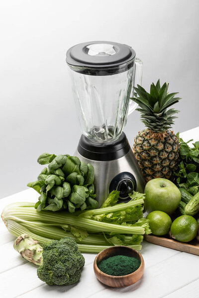overhead view of blender near tasty fruits and organic vegetables on white 