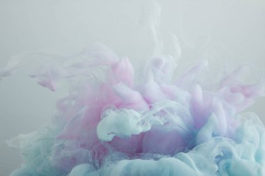 Gri üzerine izole açık mavi ve pembe boya girdaplarının yakın görünümü