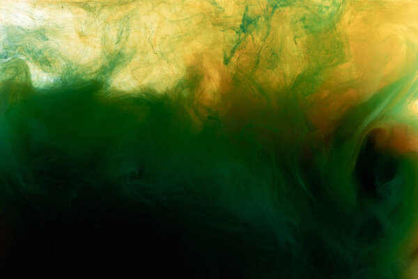 Close up view of dark green and orange paint mixing in water 