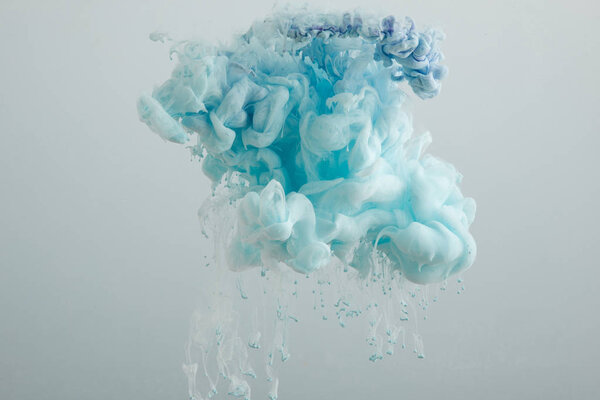 Вид на светло-голубые вихри краски, изолированные на сером
