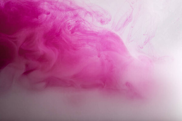 Close up view of bright pink and white paint swirls in water