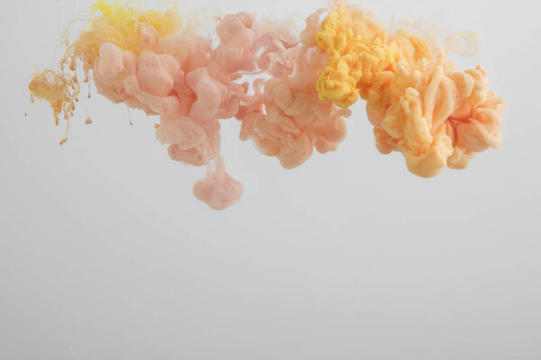 Close up view of light orange and pink paint swirls isolated on grey