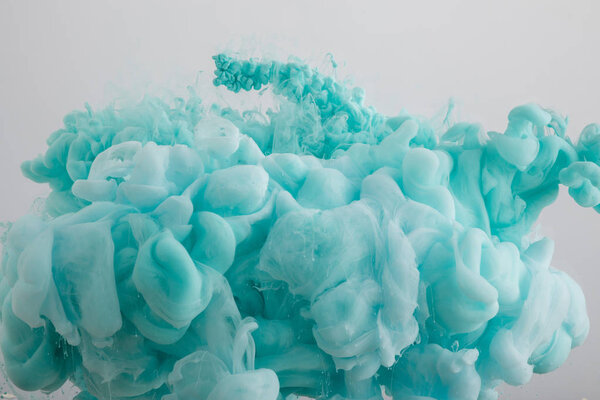 Вид на светло-голубые вихри краски, изолированные на сером
