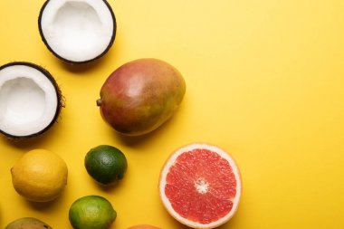 kopya alanı ile sarı arka plan üzerinde narenciye, mango ve hindistan cevizi üst görünümü