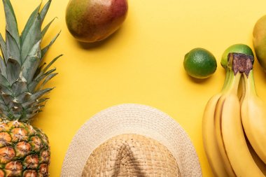 ananas, muz, limon ve sarı arka plan üzerinde mango yakın hasır şapka üst görünümü