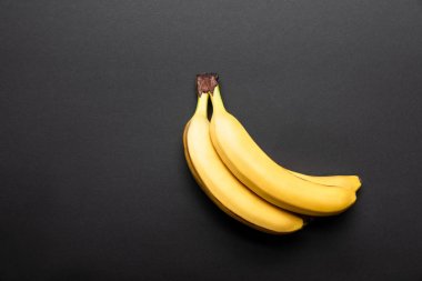 top view of ripe yellow bananas on black background with copy space clipart