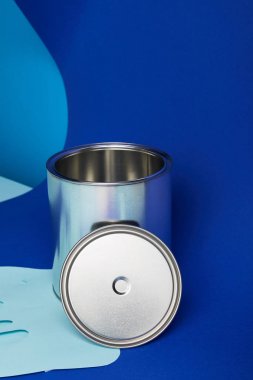 silver can on dripping paper cut paint on bright blue background clipart