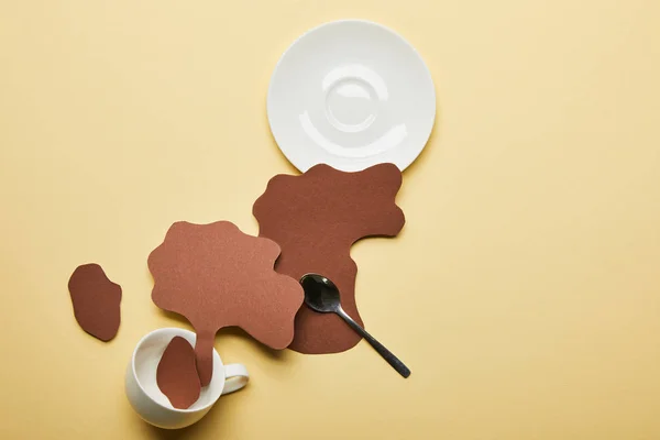 剪纸咖啡在米色背景上的杯子 碟子和勺子附近溢出的顶视图 — 图库照片