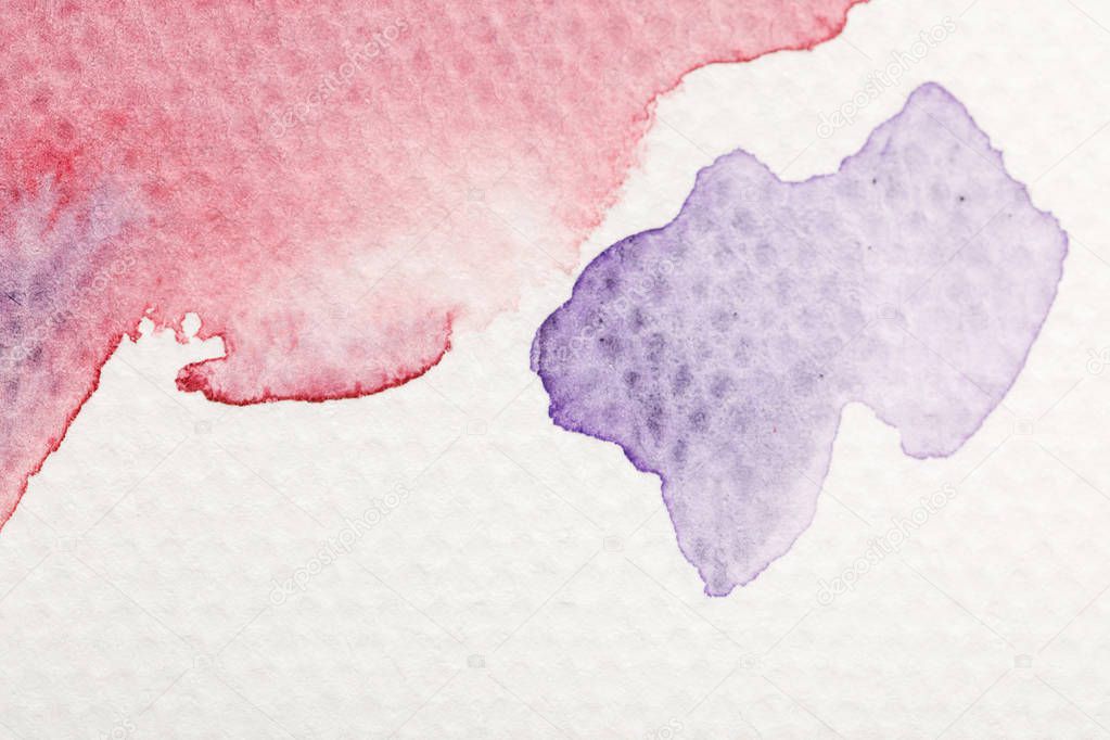 close up view of purple and red watercolor pale paint spills on white background