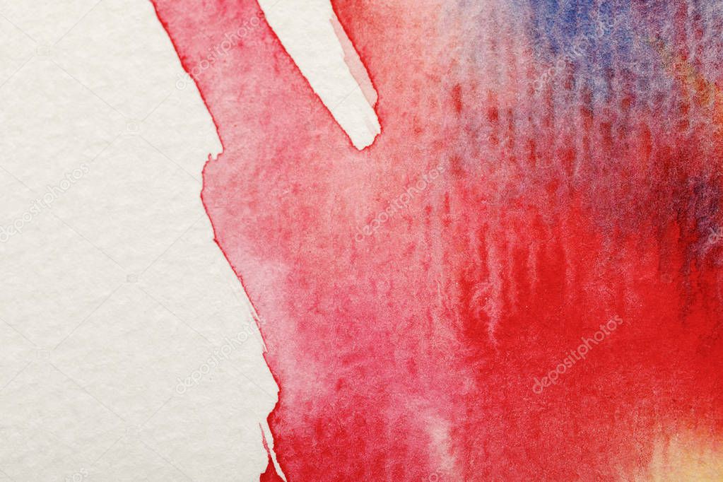 close up view of mixed bright blue and red watercolor paint spills on white background