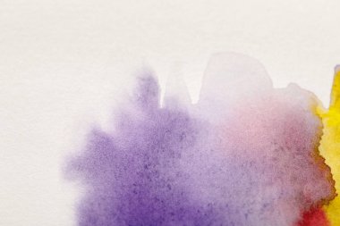 close up view of yellow, purple and red watercolor paint spills on white background clipart