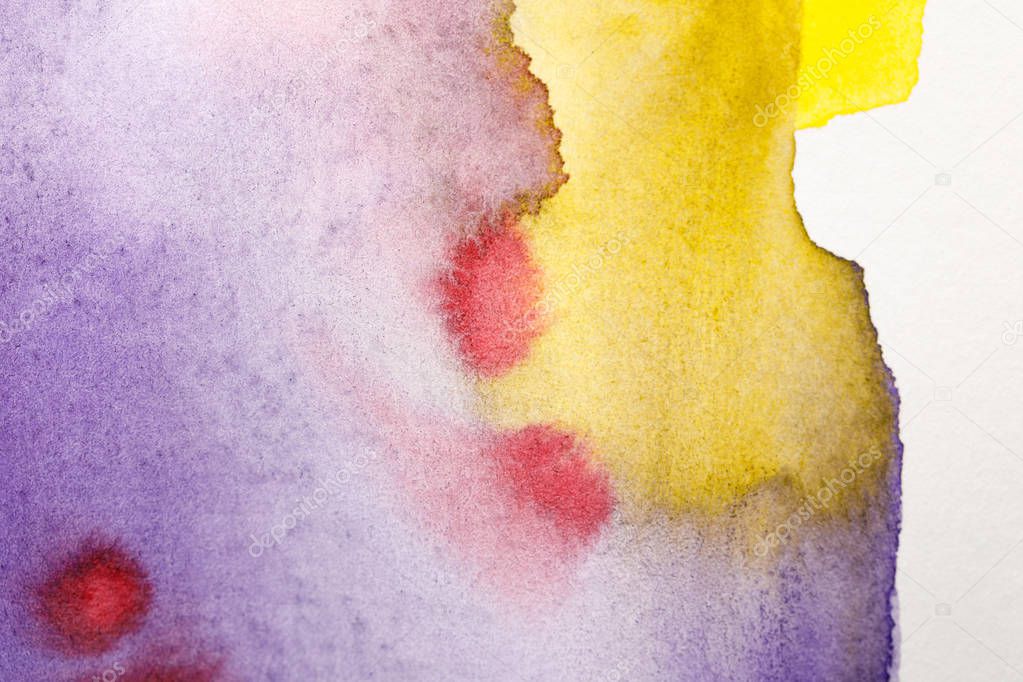 close up view of multicolored yellow, purple and red watercolor paint spills 