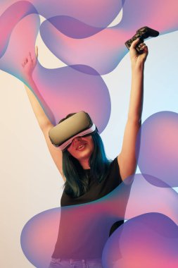 KYIV, UKRAINE - APRIL 5, 2019: Happy young woman in virtual reality headset with raised hands holding joystick on beige and blue background with abstract purple illustration clipart