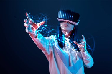 young woman in vr headset gesturing among glowing cyber illustration on dark background clipart