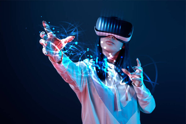young woman in vr headset gesturing among glowing cyber illustration on dark background