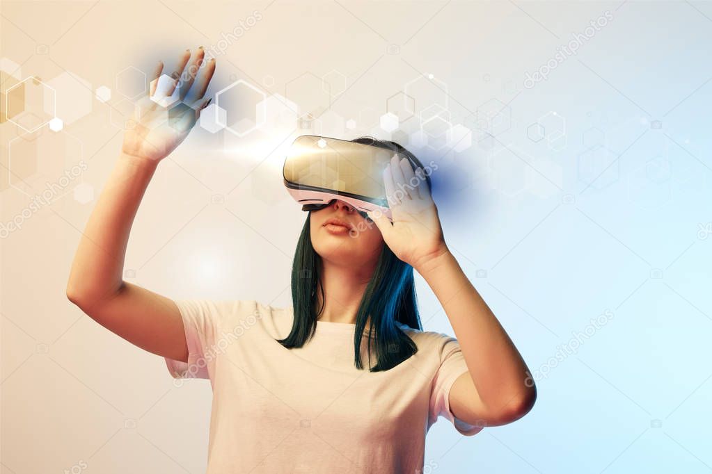 young woman in virtual reality headset pointing with hands at glowing abstract  illustration on beige and blue background