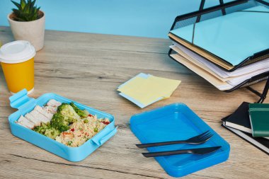 mavi arka plan üzerinde ahşap masa üzerinde kağıtları ile işyerinde lezzetli ve sağlıklı gıda ile plastik öğle yemeği kutusu