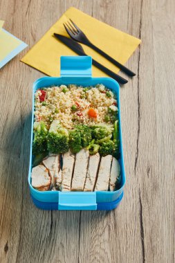 Ahşap masa üzerinde plastik öğle yemeği kutusunda brokoli ve tavuk ile lezzetli risotto Seçici odak