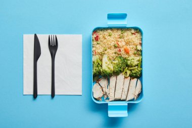 Mavi arka plan üzerinde risotto, brokoli ve tavuk ile öğle yemeği kutusunun üst görünümü