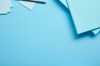 Mavi arka plan üzerine kağıtlar, yapışkan notlar ve kalem üst görünümü