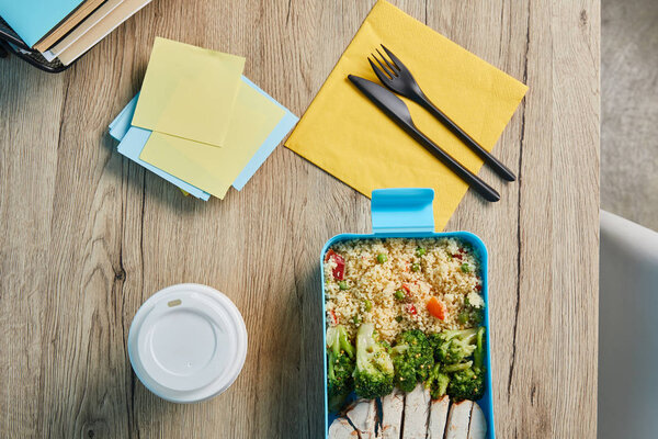 Top view of workplace with sticky notes and healthy delicious lunch with risotto and chicken on wooden table