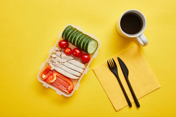 黄色の背景に鶏肉と新鮮な野菜とコーヒーのカップとランチボックスのトップビュー — ストック写真