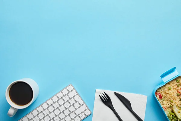 コンピュータキーボード コーヒーカップ おいしい食事と青い背景にナイフと使い捨てフォークとランチボックスのトップビュー — ストック写真
