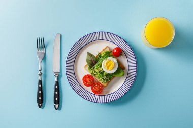 servis kahvaltı üst görünümü, mavi arka plan guacamole ve portakal suyu ile tost