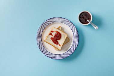 mavi arka plan üzerinde reçel ile kase tabak ve kaşık üzerinde tost üst görünümü