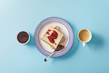 tost, kaşık, reçel ve mavi arka plan üzerinde kahve fincan ile kase üst görünümü