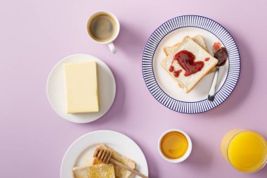 tereyağı, kahve, portakal suyu, mor arka plan tabaklarda bal ve reçel ile tost üst görünümü 