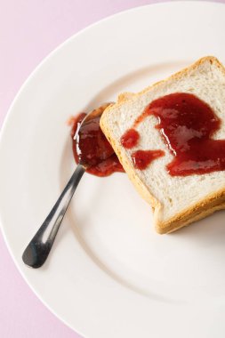 menekşe üzerinde izole beyaz plaka üzerinde reçel ile tost ve kaşık yakın görünümü