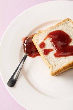 close up view of toasts and spoon with jam on white plate isolated on violet clipart