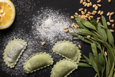 top view of raw green ravioli with pine nuts, flour, green sage and lemon clipart