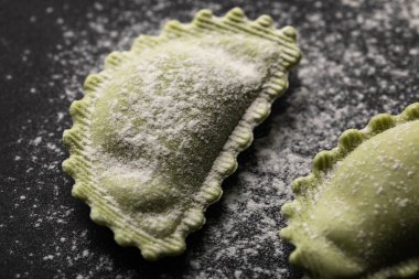 siyah yüzeyde un ile yeşil taze ravioli yakın görünümü