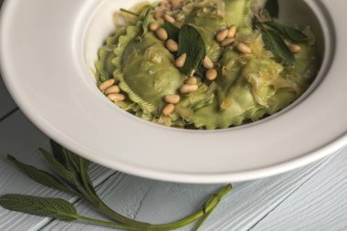 ahşap masa üzerinde erimiş peynir, çam fıstığı ve adaçayı ile lezzetli ravioli yakın görünümü