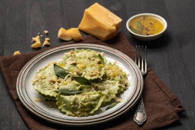 adaçayı, peynir ve çam fıstığı ile lezzetli yeşil ravioli çatal ve peçete ile siyah ahşap masa üzerinde servis