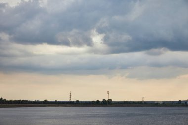 mavi bulutlar, gün batımı arka plan üzerinde elektrik direkleri ile nehir ve sahil