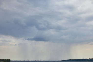 overcast view of blue clouds and rain upon forest coast clipart