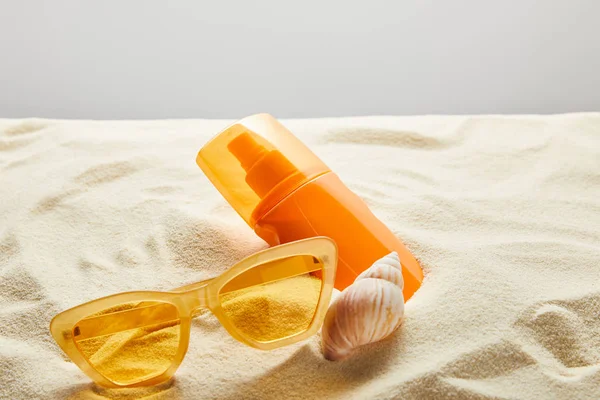 Yellow Stylish Sunglasses Sunscreen Orange Bottle Sand Seashell Grey Background — 스톡 사진