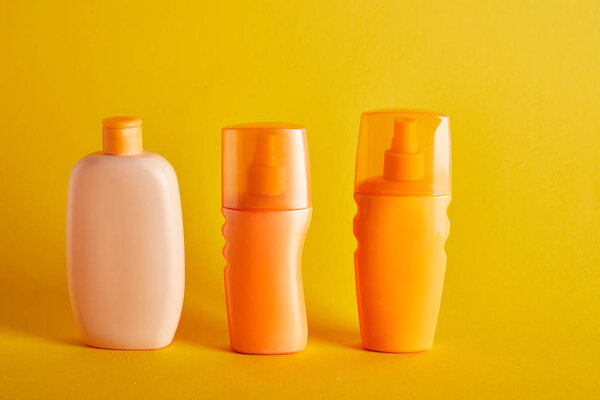 suntan cosmetics in bottles on dark yellow background