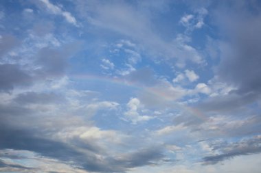 view of rainbow on blue sky background and blue clouds clipart