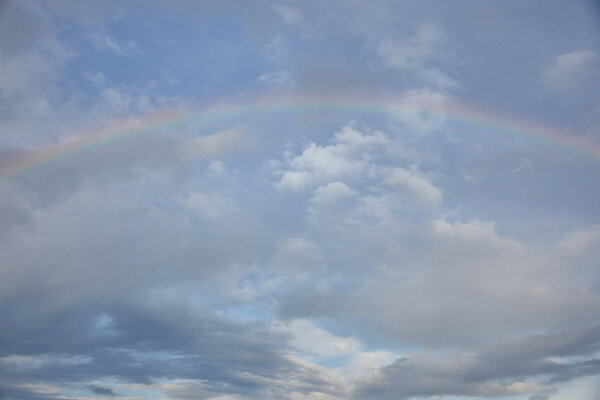 rainbow on blue sky with white clouds on background