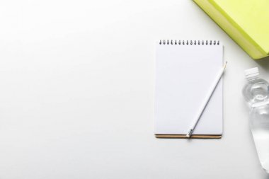 Beyaz arka planda kutu yakın kalem ile şişe ve boş Notebook su üst görünümü